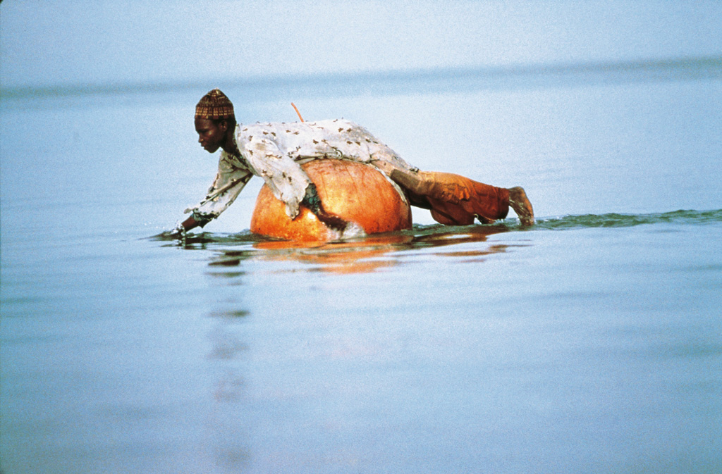 Fisherman while floating on a pumpkin that will contain fish caught with nets, Lake Chad. Credit: Universal Images Group North America LLC / DeAgostini / Alamy Stock Photo.